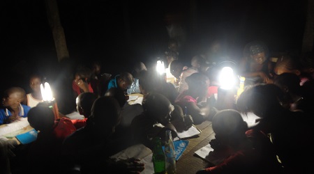 Students studying at night with solar lanterns that were dontated to the school.